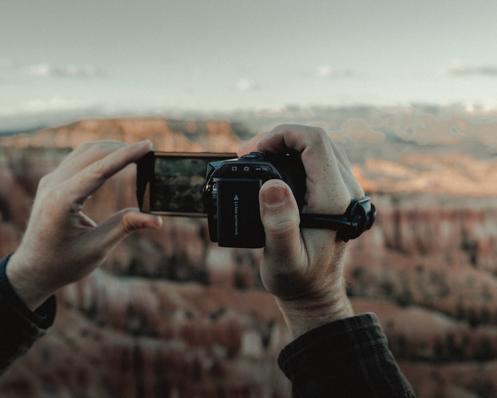 person holding black smartphone taking photo of brown field during daytime