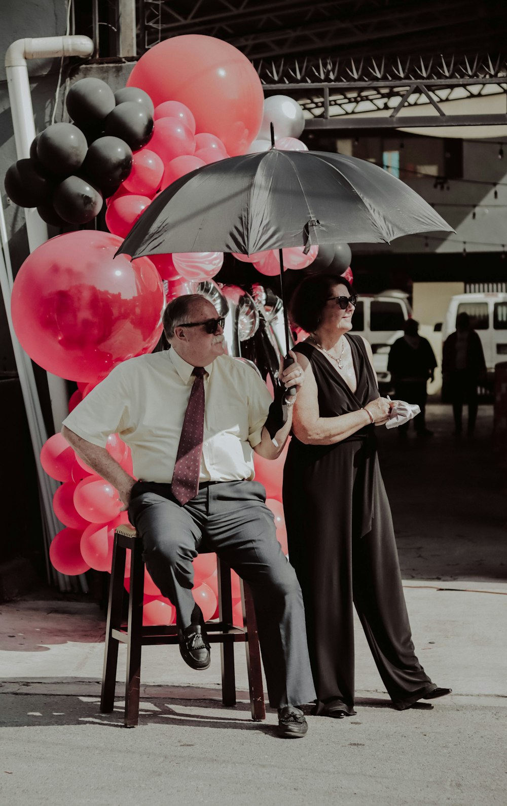 a man and a woman sitting on a chair under an umbrella