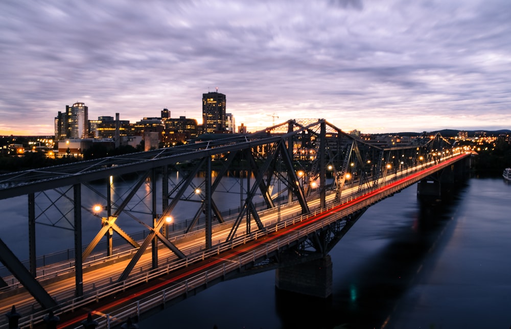 bridge over river near city buildings during night time