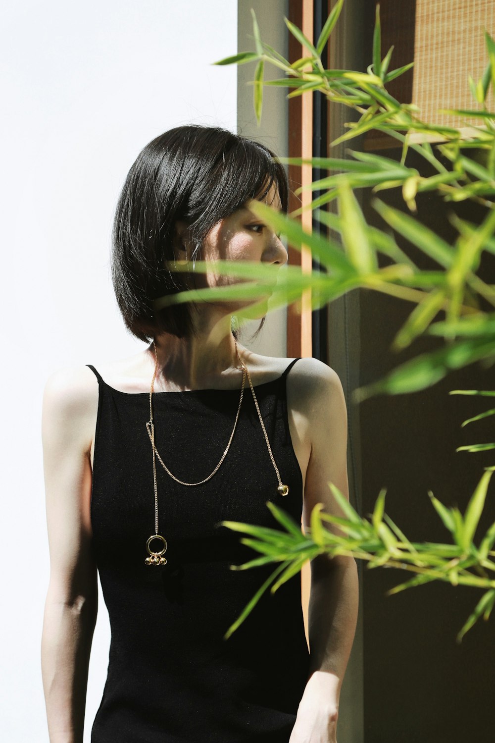 woman in black tank top standing beside green plant