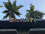 Colorful letters spelling 'Be Happy' are mounted on a structure, with palm trees in the background against a clear blue sky.
