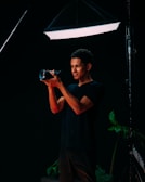 man in black crew neck t-shirt holding black dslr camera