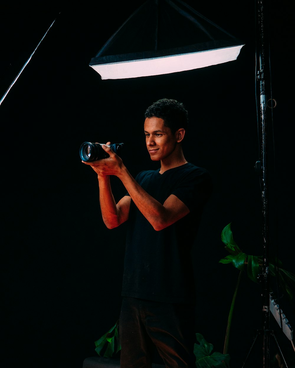 man in black crew neck t-shirt holding black dslr camera