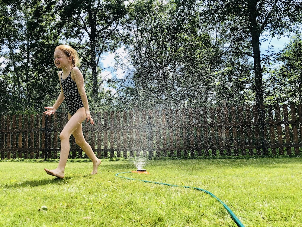 woman in black tank top and black shorts standing on green grass field during daytime