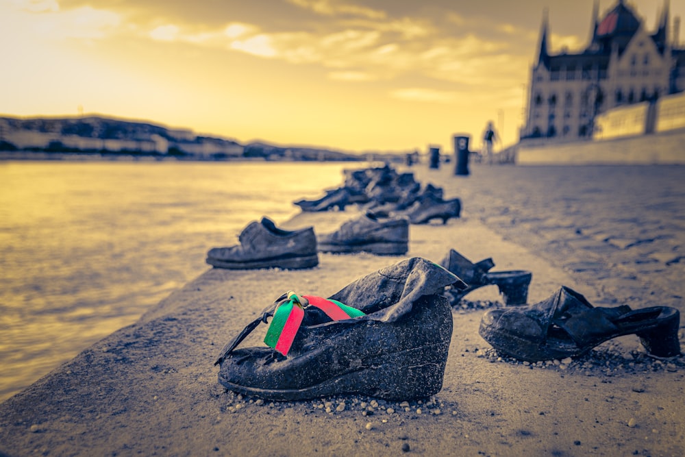 chaussures noires et rouges sur le sable brun près du plan d’eau pendant la journée