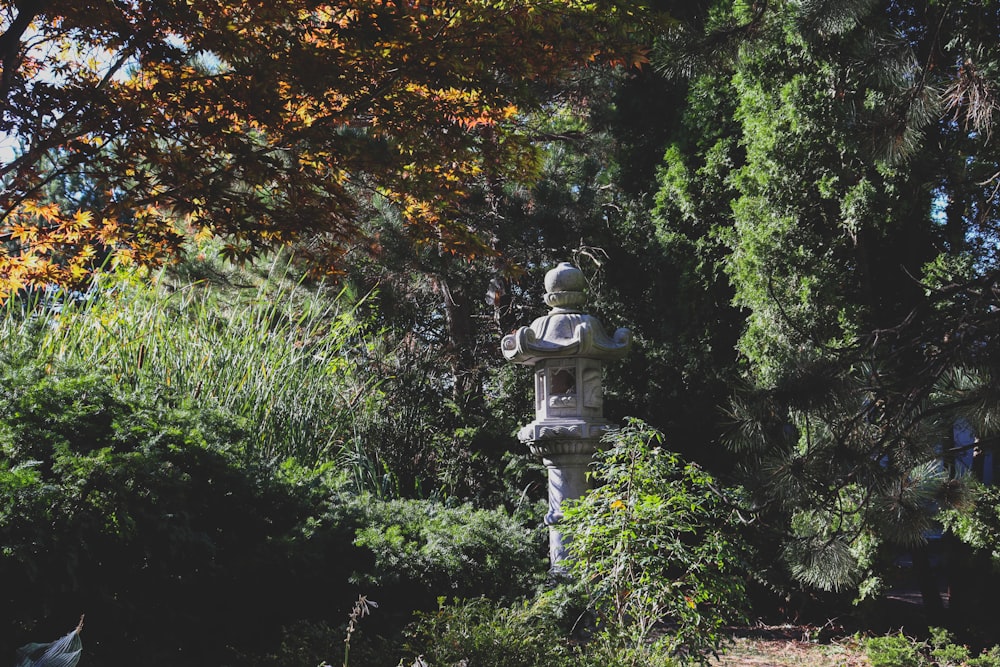 gray concrete outdoor lamp surrounded by green plants and trees during daytime