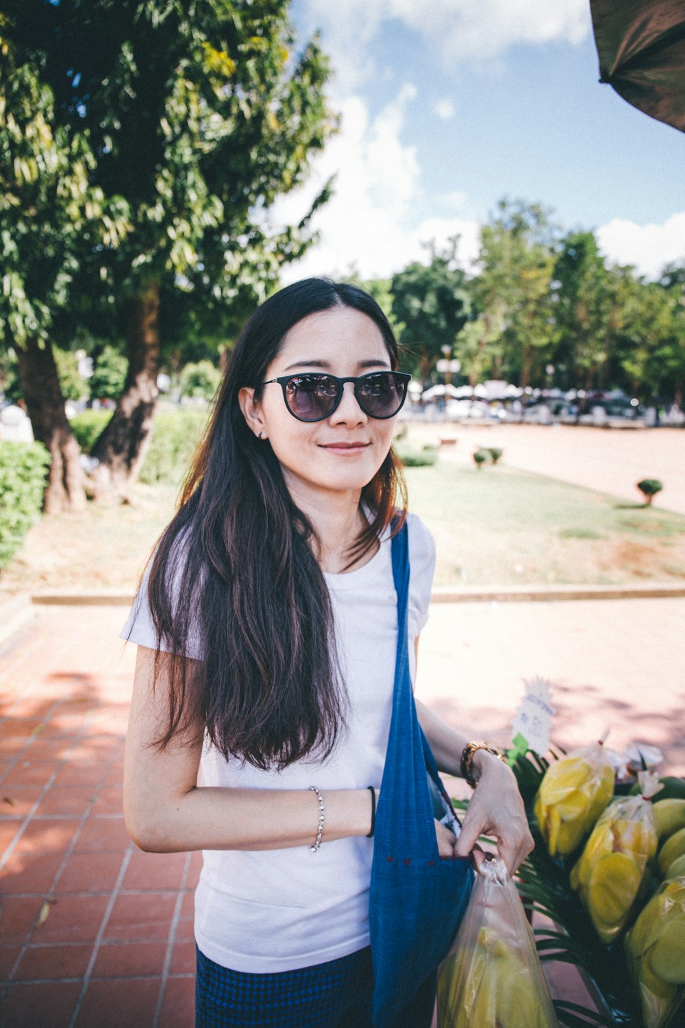 woman in white shirt and blue denim vest wearing black sunglasses standing on brown sand during