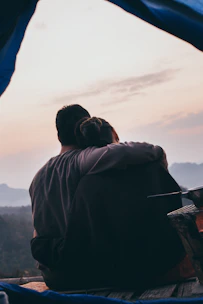 Close-up of a couple sharing a quiet, cinematic embrace with deep navy and turquoise tones softly blending.