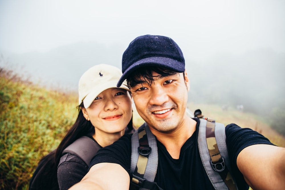 man in black shirt beside woman in white fitted cap