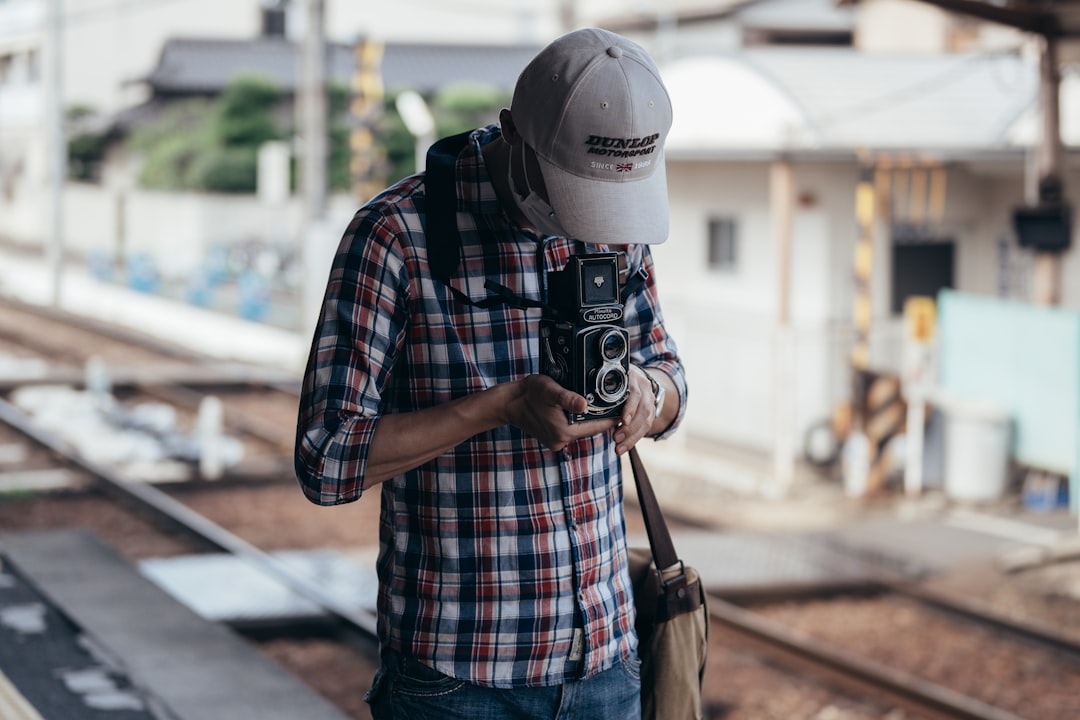 man in blue red and white plaid shirt holding black dslr camera