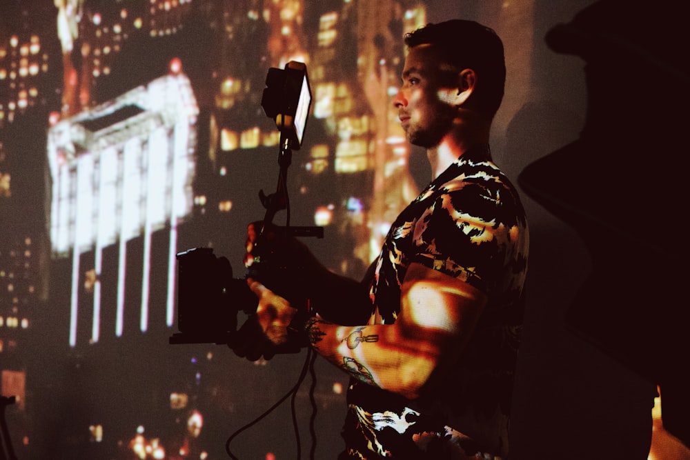 man in black and white floral shirt holding string lights