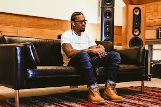 Happy customer lounging on a couch, wearing headphones connected to nubian entertainment plus speaker set.