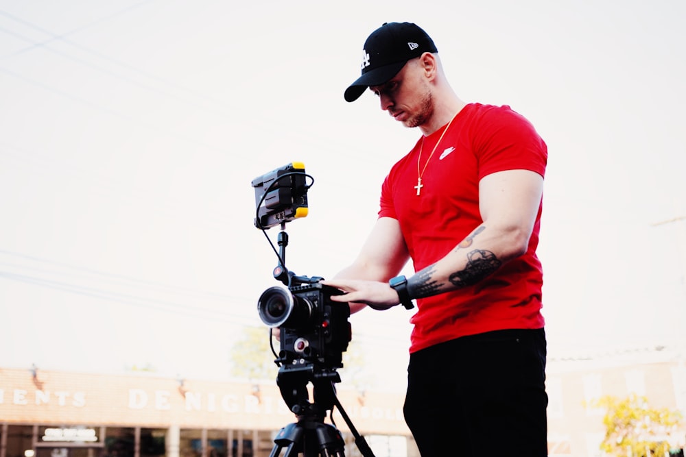 man in red polo shirt holding black dslr camera