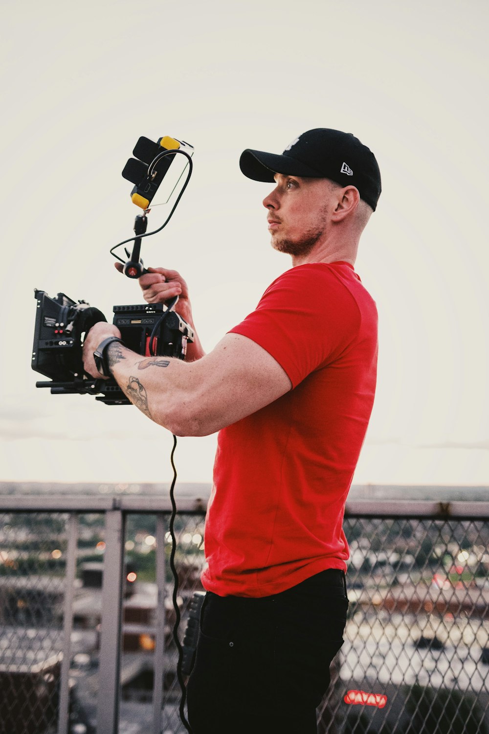 man in red crew neck t-shirt holding black dslr camera