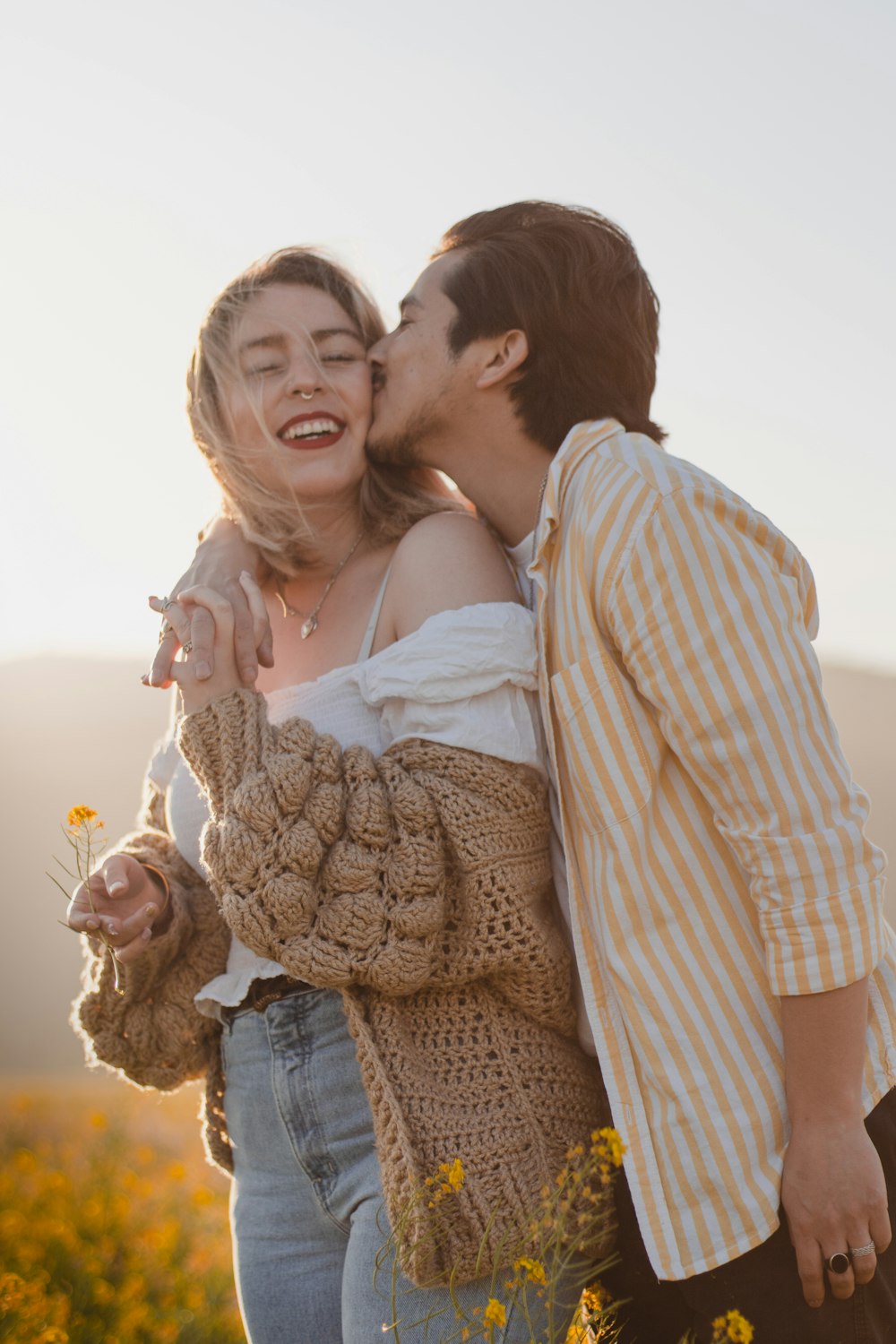 man in brown and white checkered dress shirt hugging woman in white dress during daytime