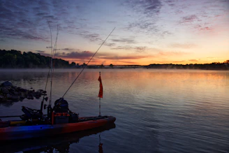 A serene lake at dawn with a fishing rod resting on a wooden dock.
