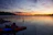 A serene morning lake view with a small wooden dock and a fishing rod resting against a chair.