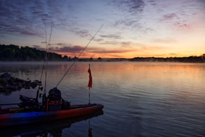 A peaceful lake scene at dawn with fishing gear set up on the shore.