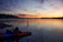 A serene morning lake view with a small wooden dock and a fishing rod resting against a chair.