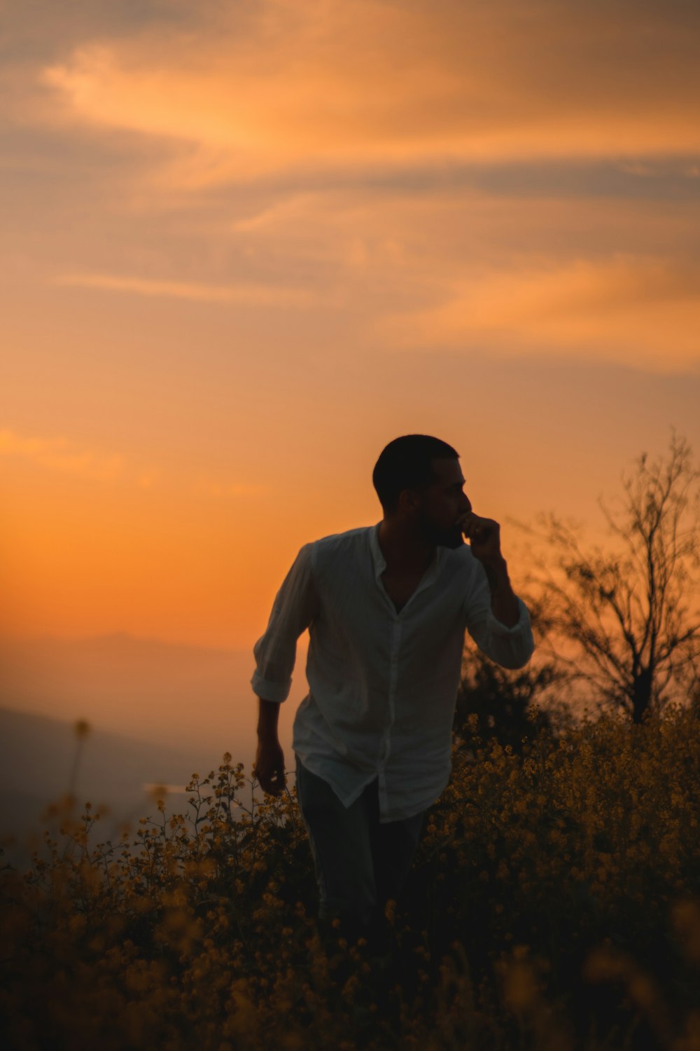 man in white dress shirt standing on green grass field during sunset