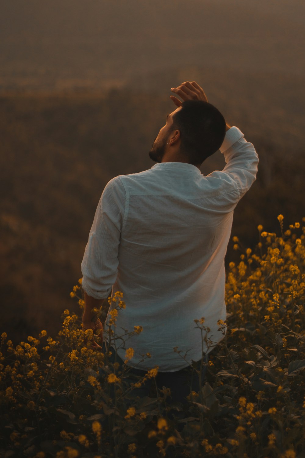 man in white shirt standing on yellow flower field during daytime