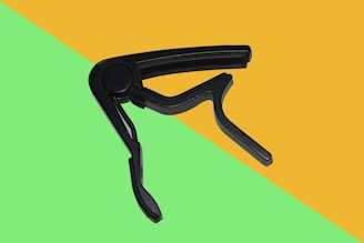 Close-up of a vibrant guitar capo clipped onto a guitar neck under stage lighting