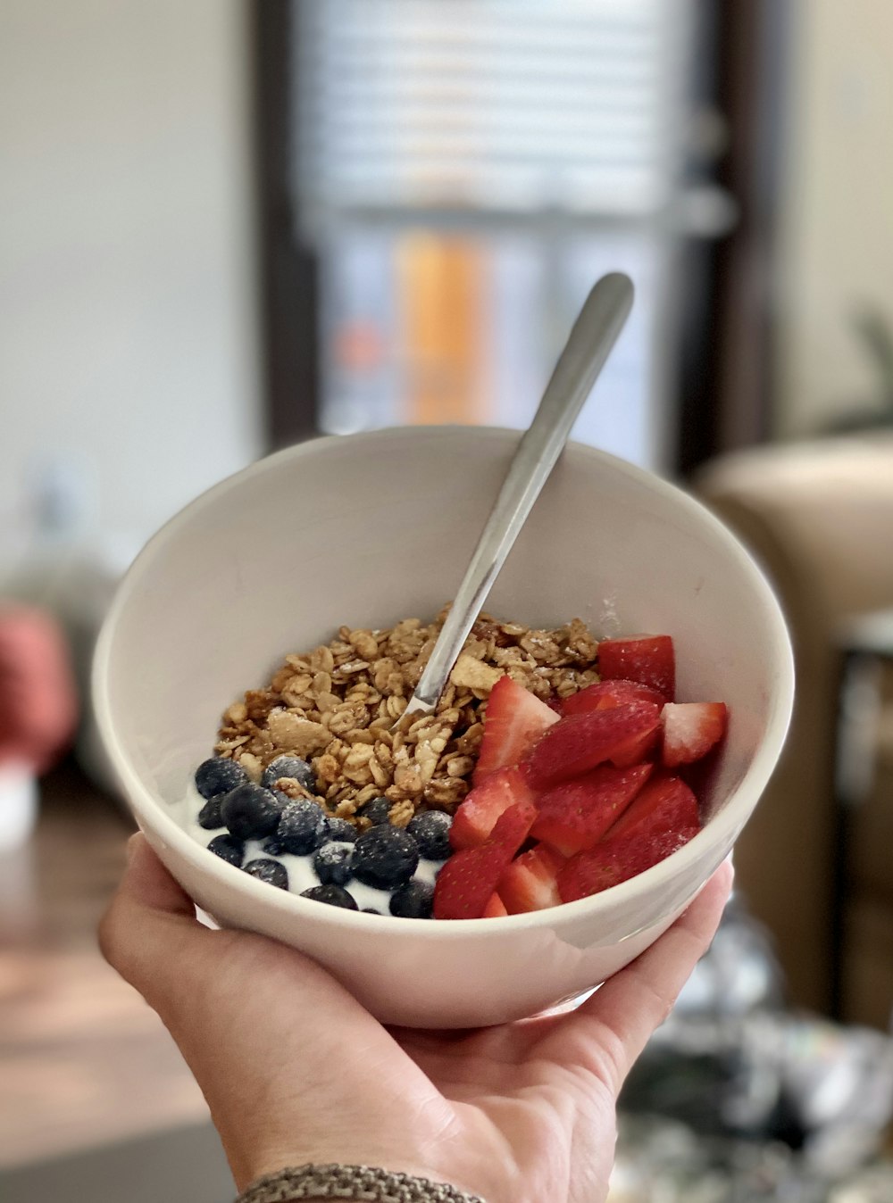 person holding white ceramic bowl with sliced strawberries