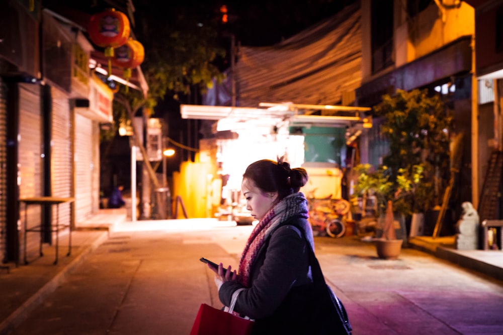 woman in black jacket sitting on red chair during night time