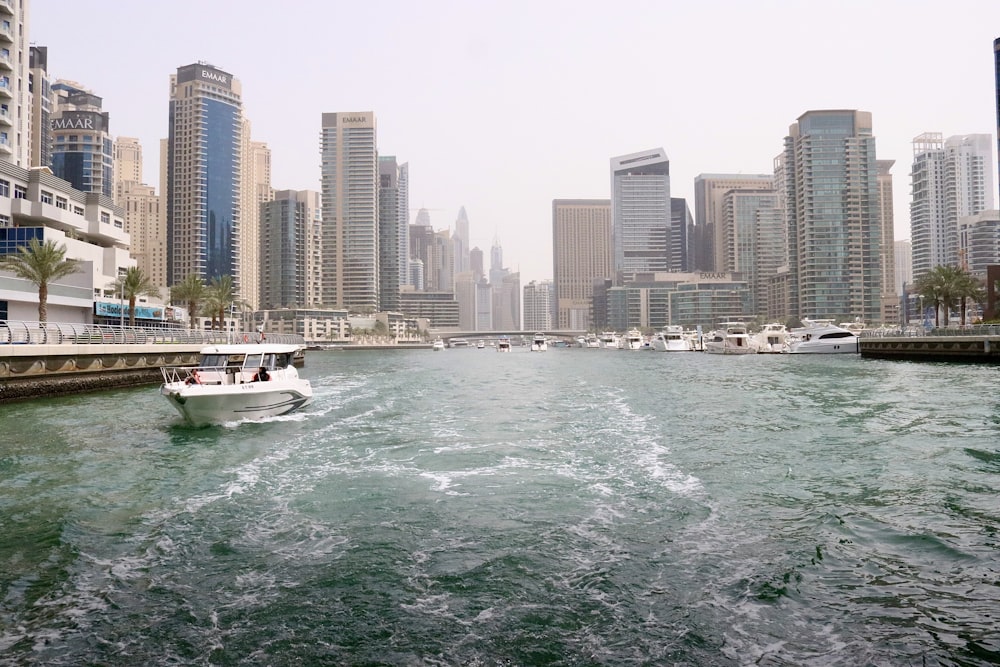 barco branco no mar perto de edifícios da cidade durante o dia