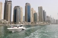 white boat on sea near high rise buildings during daytime