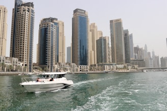 white boat on sea near high rise buildings during daytime