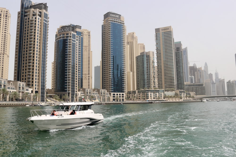 white boat on sea near high rise buildings during daytime