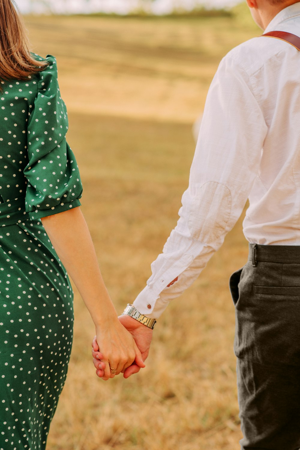 woman in green and white polka dot dress holding hands with man in white long sleeve