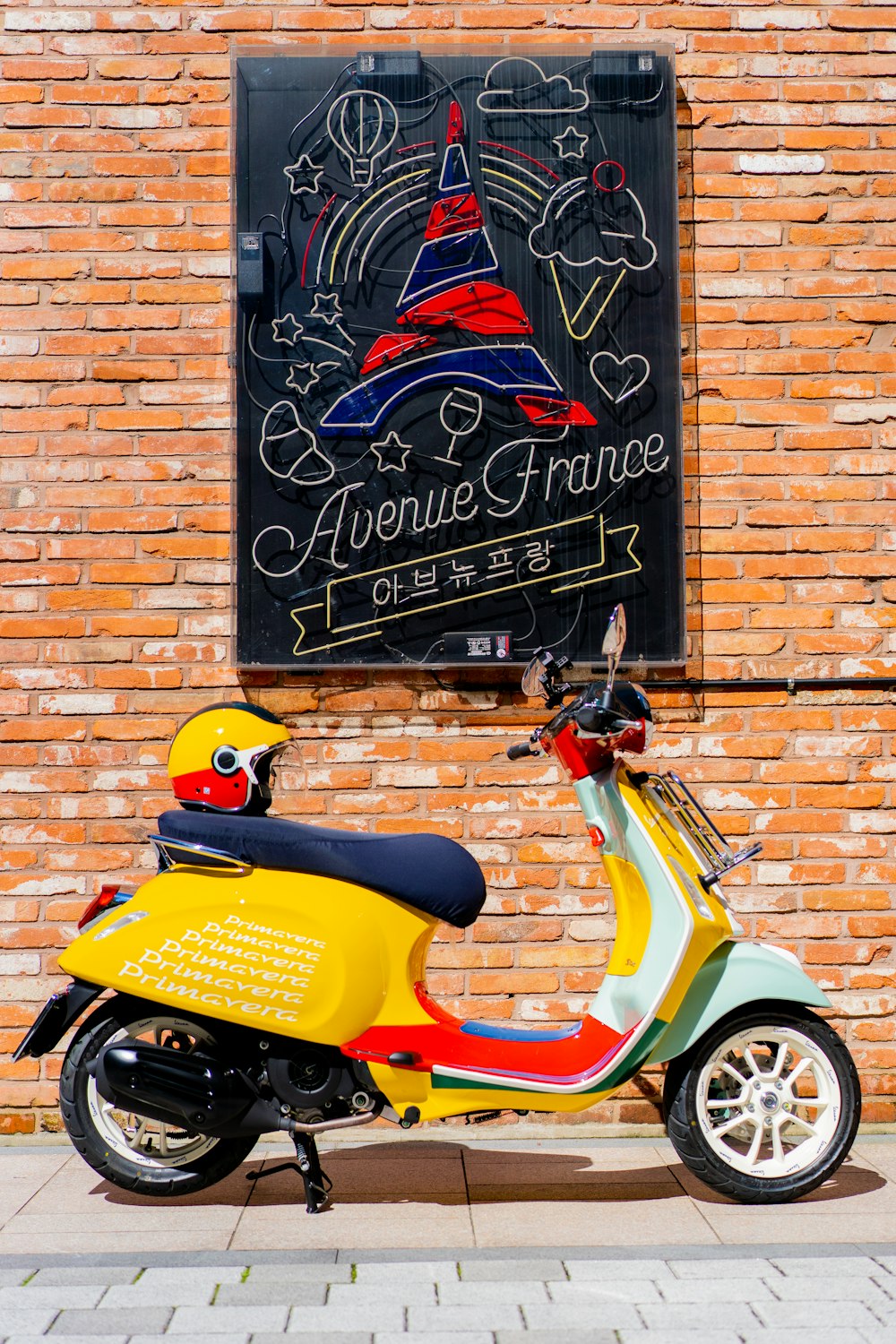 orange and black motor scooter parked beside brick wall