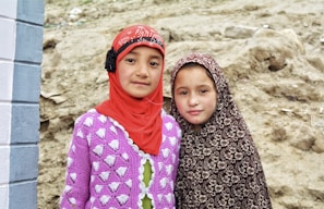 2 women wearing hijab standing on brown sand during daytime