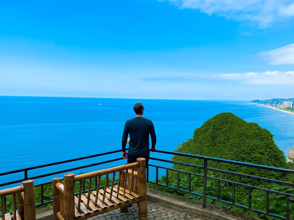 man in black jacket standing on brown wooden bridge during daytime