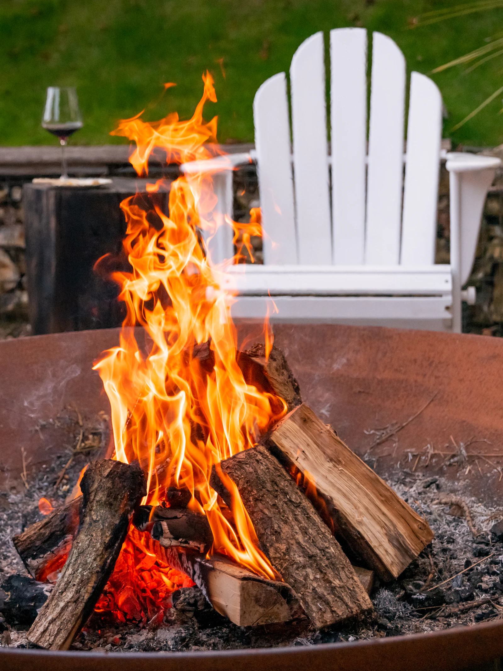 Split firewood burning low inside a stone fire pit at the centre of a paved terrace