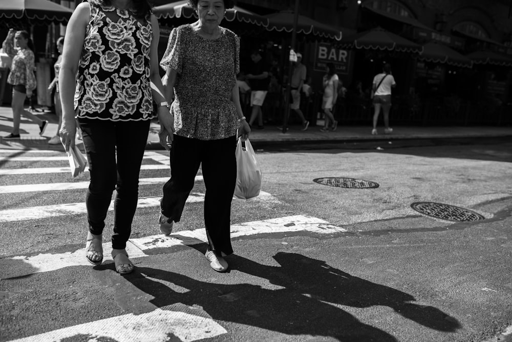 grayscale photo of woman in black and white floral long sleeve shirt and black pants