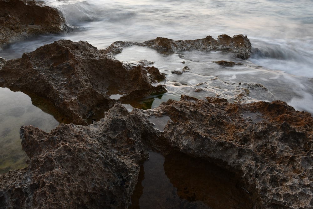 brown rocky shore with ocean waves crashing on rocks