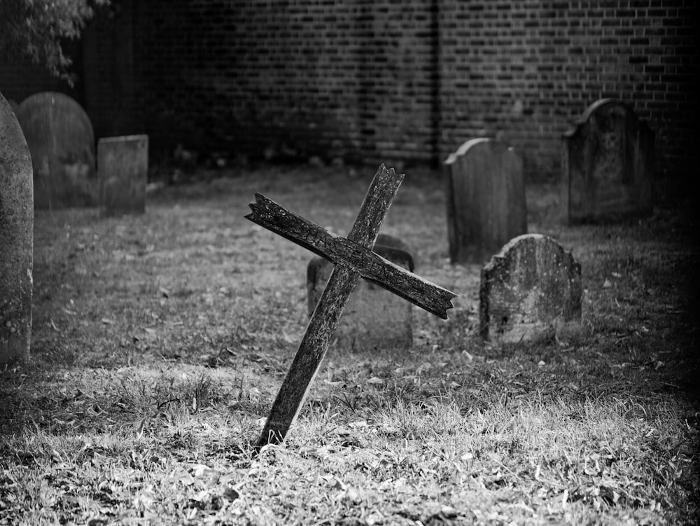 grayscale photo of cross on grass field