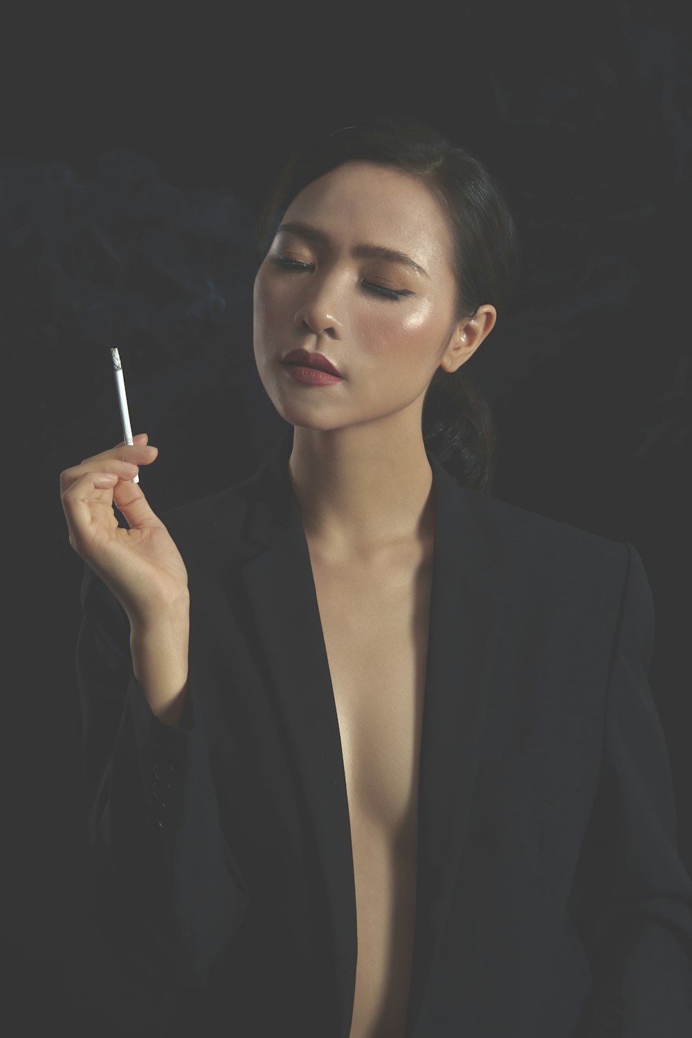 woman in black blazer holding cigarette stick