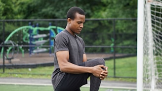 man in blue polo shirt and black pants sitting on gray concrete pavement during daytime