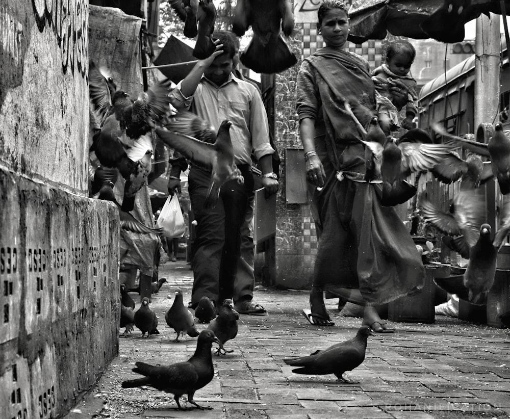 grayscale photo of man and woman with black birds on their hands