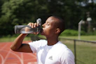 man in white crew neck t-shirt drinking from black sports bottle