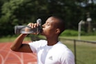 man in white crew neck t-shirt drinking from black sports bottle