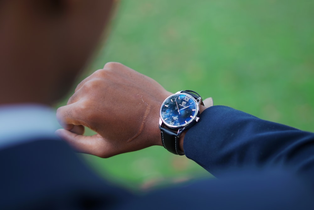 person wearing black and silver round analog watch