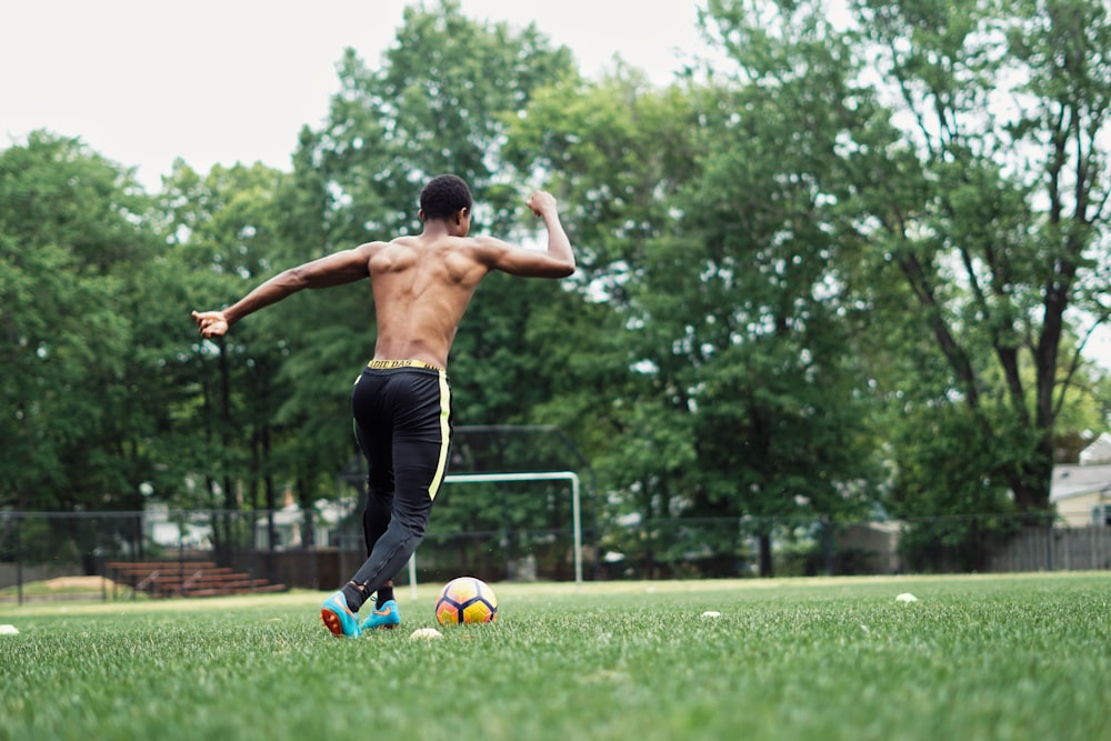 man in black shorts doing push up on green grass field during daytime
