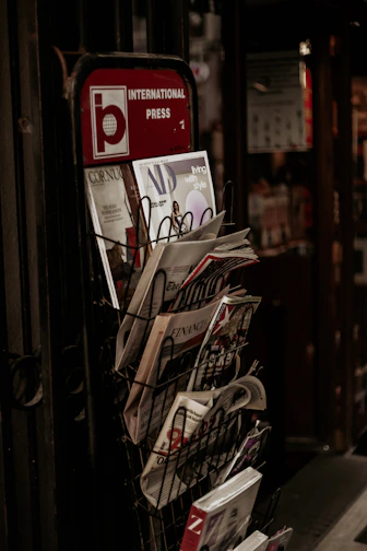 A sleek metal magazine rack filled with art and design magazines next to a comfy reading chair.