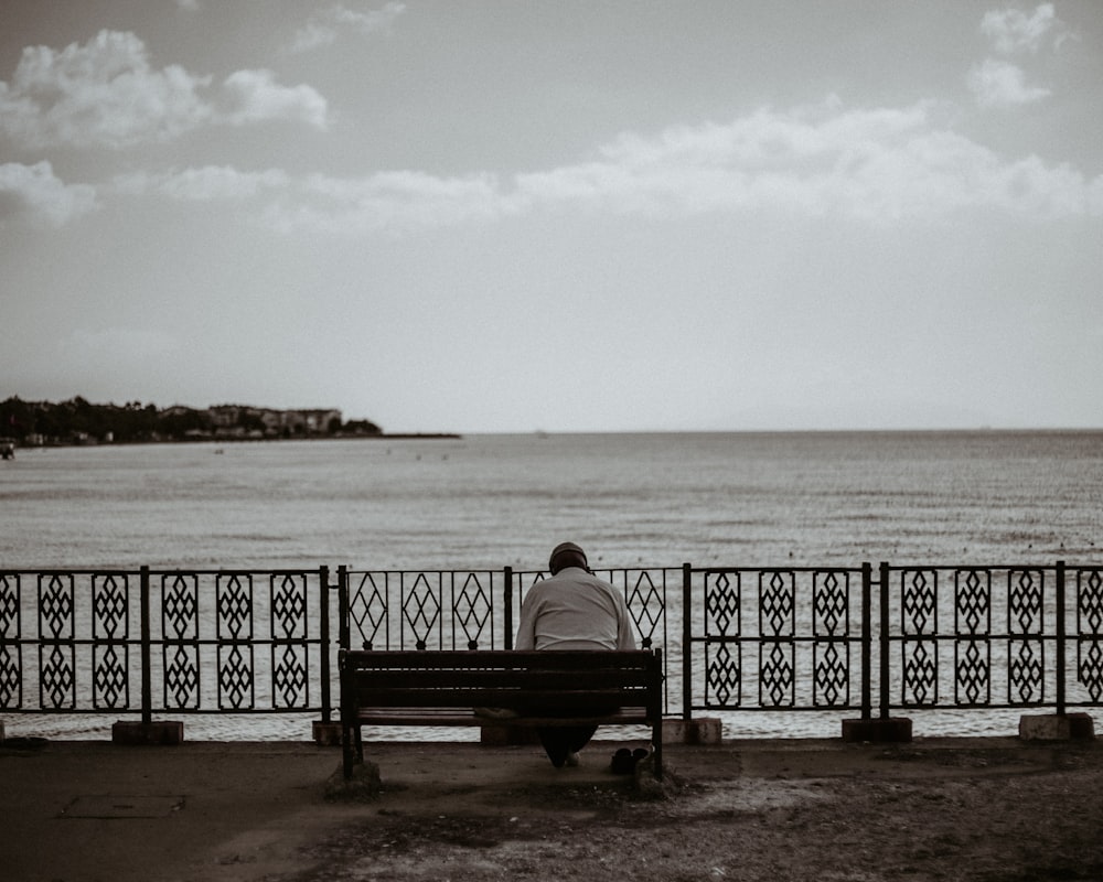 woman sitting on bench near sea during daytime