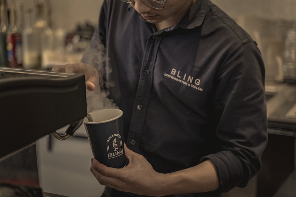 man in black polo shirt holding black ceramic mug